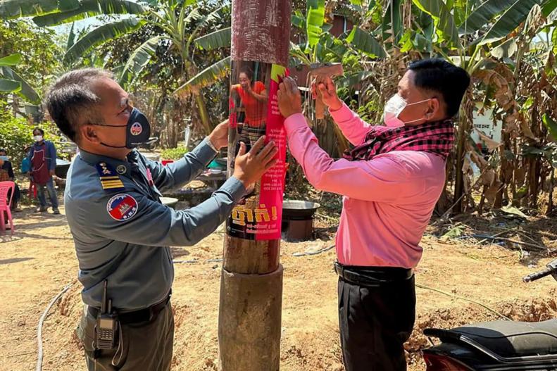 ကမ္ဘောဒီးယားတာဝန်ရှိသူများက ကြက်ငှက်တုပ်ကွေးရောဂါအန္တရာယ်သတိပေးသည့် ပိုစတာများ ကပ်နေစဉ် [ Photo: Associated Press ] 